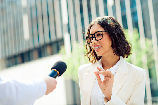 Confident young businesswoman speaks in an interview outdoors with a professional demeanor
