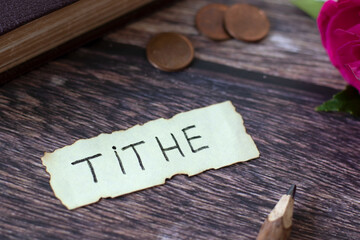 Tithe, handwritten text with holy bible and coin money on wooden background. Christian blessing and...