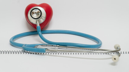 Stethoscope rests on red heart shaped object, symbolizing healthcare and cardiology. image conveys...
