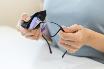 Close-up person cleaning eyeglasses with microfiber fabric.