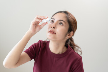 asian young woman using medical eye drops to treat dry eye and irritation.
