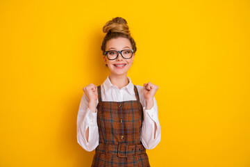 Teen girl student smiling against a vibrant yellow background in stylish formalwear showcasing happiness and academic enthusiasm