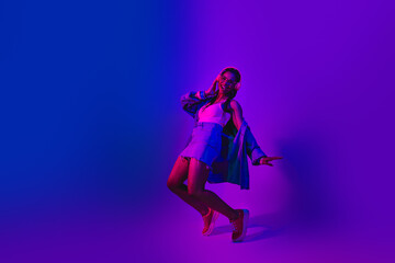 Vibrant Nightlife Scene Featuring a Fashionable Woman Dancing Under Neon Lights in an Ultraviolet...