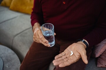 Older man taking medication with glass of water at home