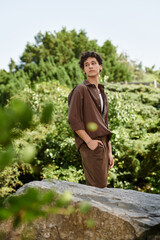 Young man enjoys summer vibes in a lush green park dressed in stylish outdoor attire