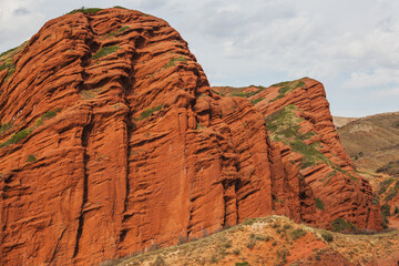 Majestic red rock formations in Kyrgyzstan's stunning landscape.  Layers of vibrant terracotta and...