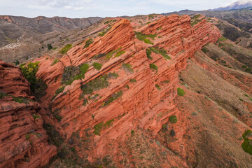 Stunning aerial view of red rock formations in the Kyrgyzstan mountains.  Layers of sedimentary...