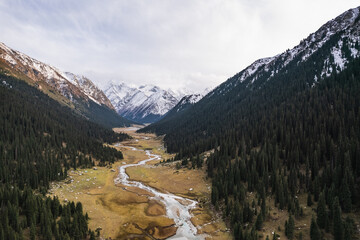 Majestic aerial view of a serene valley nestled in the snow-capped mountains of Ala-Kul Lake,...