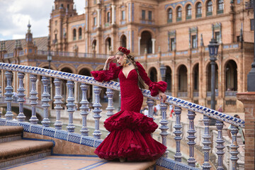 Young, beautiful, blonde woman in red flamenco dress, flowers in her hair and gold jewelry,...