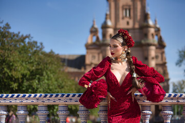 Young, beautiful, blonde woman in red flamenco dress, flowers in her hair and gold jewelry,...