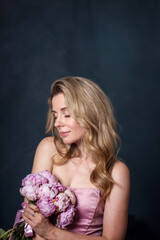 beautiful woman with peonies in her hands on a light background