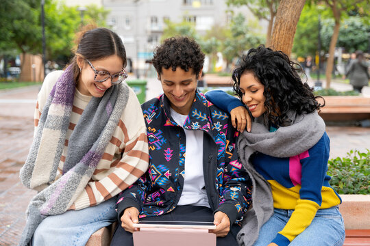 Young latin american friends sharing a digital tablet in the city