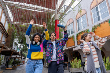 Young latin friends listening to music and walking in the city