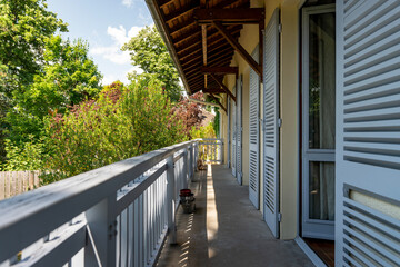 Vue depuis un balcon à l’étage longeant une maison ancienne, avec plusieurs baies vitrées et...