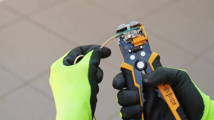 Cropped shot of a man in safety gloves removing insulation with wire stripper