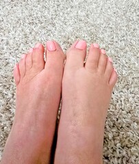 Female Feet with Pink Toenail Polish on a White Carpet 