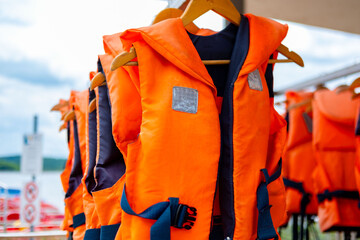 Bright orange life vests hanging, Safety equipment water sports, Summer activity preparation, water...
