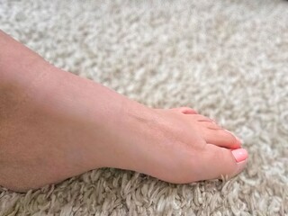 Side View Female Foot with Pink Toenail Polish on a White Carpet 