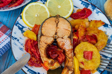 The best recipe of salmon baked with vegetables and lemon on a wooden table