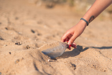 Volunteer collecting plastic bottle on the beach during a cleanup event
