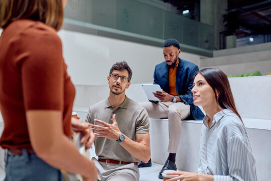 Group of young professionals engaging in a lively discussion while sharing innovative ideas during a casual meeting in the office lobby - Powered by Adobe