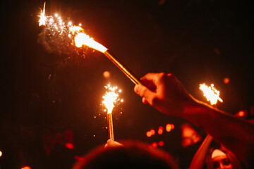 Hand Holding Sparkler in a Dark Crowded Nightclub Party