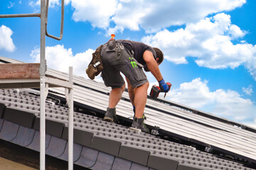 Worker Fixing Solar Panel on Rooftop with Power Drill in Sunny Weather – Symbol of Modern Energy...