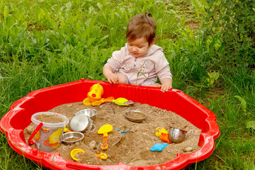 a little girl sees a sandbox for the first time, carefully examines the toys in it