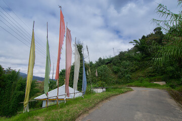 Beautiful way to Okhrey village, colourful Buddist prayer religious flags waving on the side of road . Okhrey is a remote village with scenic natural vista in background, in Sikkim, India.