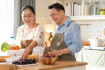 Asian senior couple cooking breakfast in the kitchen. husband helping wife on the morning weekend....