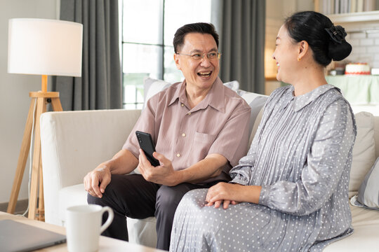 Asian senior couple spend time having fun using smartphone apps, grandparents enjoy online entertainments, watching videos, older generation and modern tech concept