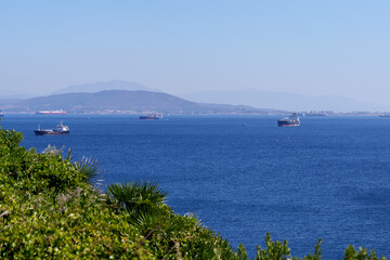 Cargo ships sailing on the strait of gibraltar, a narrow waterway separating europe and africa, highlighting maritime transport and global trade