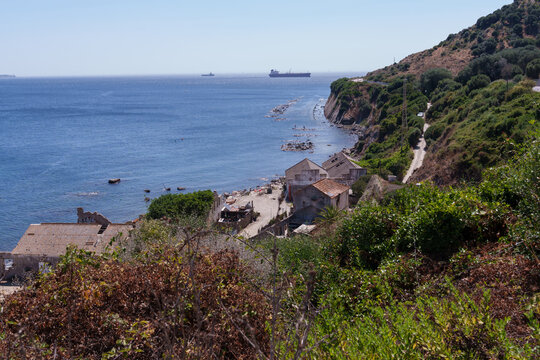Cargo ships navigating the strait of gibraltar with an abandoned coastal mining village in the foreground - Powered by Adobe