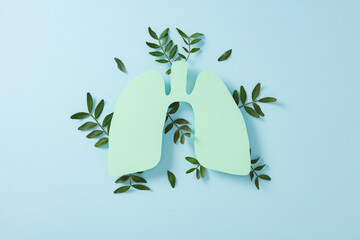 Green lungs paper cutout with leaves on blue background, symbolizing eco-friendly breathing, clean air, and environmental respiratory health