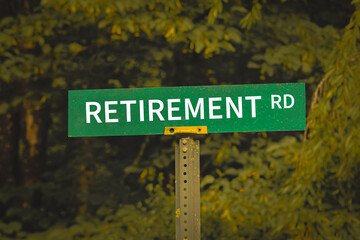 a green road sign reading RETIREMENT Road set against a blurred background of lush green foliage. financial design element, banner or background with copy space