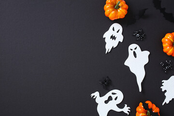 Happy Halloween flat lay with pumpkins, ghosts, bats, and spiders on dark background with copy...