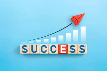 Red paper plane and success words on wooden cubes