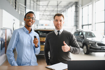 Dealer with male customer signing documents at auto salon. Bearded man in buying new vehicle at car...