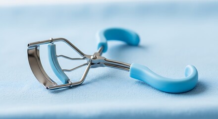 Pastel Blue Eyelash Curler: Close-up Product Shot on Soft Blue Fabric