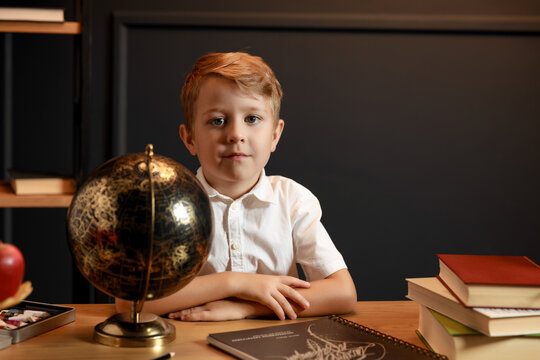 Child Doing Homework with Books and Globe &ndash; Back to School Theme