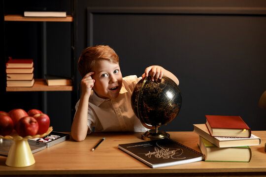 Child Doing Homework with Books and Globe &ndash; Back to School Theme