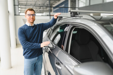 Young man is choosing a new vehicle in car dealership