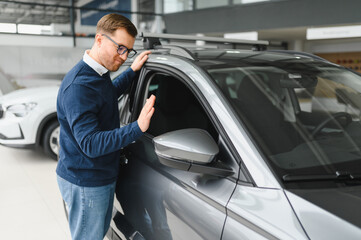 Young man is choosing a new vehicle in car dealership