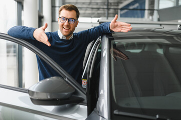 Young man is choosing a new vehicle in car dealership