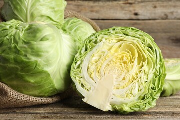 Fototapeta premium Fresh whole and cut cabbages on wooden table, closeup