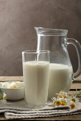 Fresh milk, mozzarella balls and flowers on wooden table, closeup. Dairy products