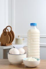 Different dairy products and eggs on wooden table indoors