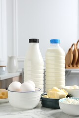 Different dairy products and eggs on white marble table indoors