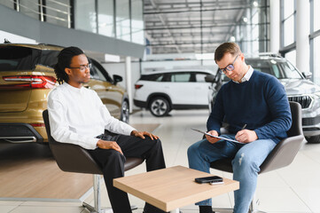 Dealer with male customer signing documents at auto salon. Bearded man in buying new vehicle at car...