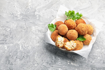 Delicious fried croquette balls with parsley in bowl on grey textured table. Space for text